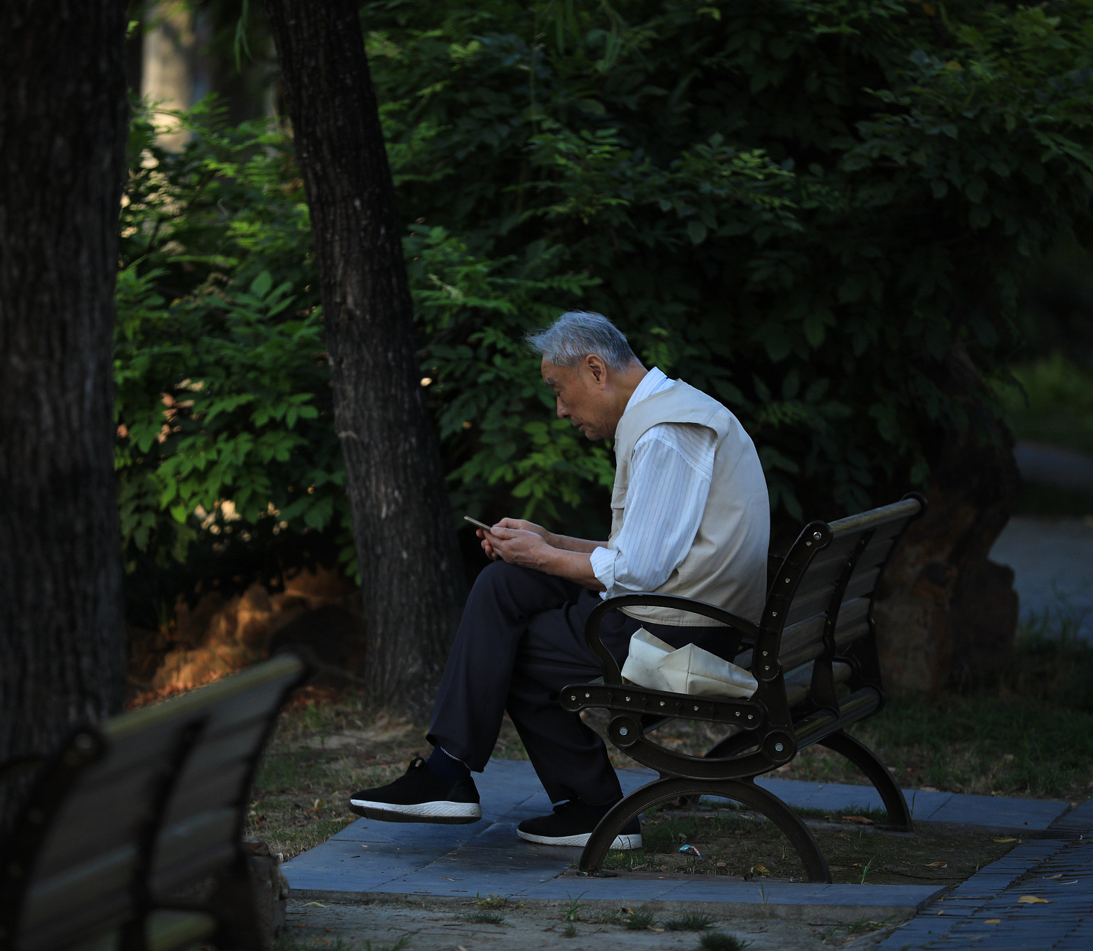 老人在公园的长椅上看手机