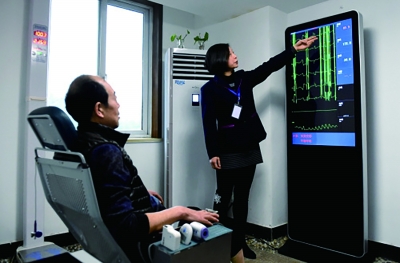 洛阳市英才社区智慧养老服务中心的工作人员在为老人讲解仪器检测得出的各项身体情况数值（新华社记者 李安/摄）