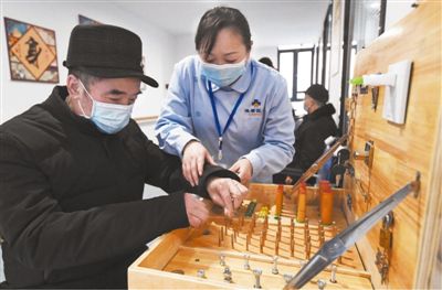近日，一位老人在重庆渝北区仙桃街道空港佳园社区养老服务站工作人员的协助下进行手指功能训练。