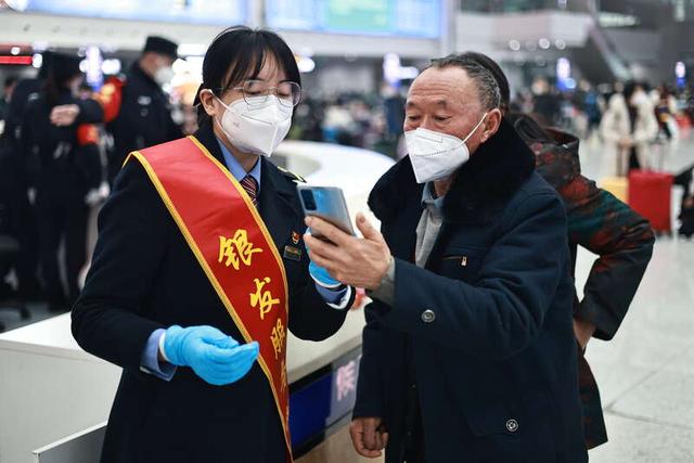 1月29日，重庆北站候车室，“银发服务队”工作人员为旅客提供咨询服务。苏志刚/摄